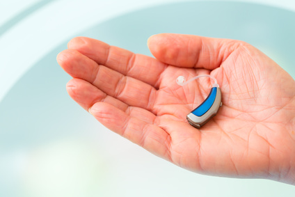 Closeup of a hand holding small inconspicuous hearing aid, such as deaf people need it